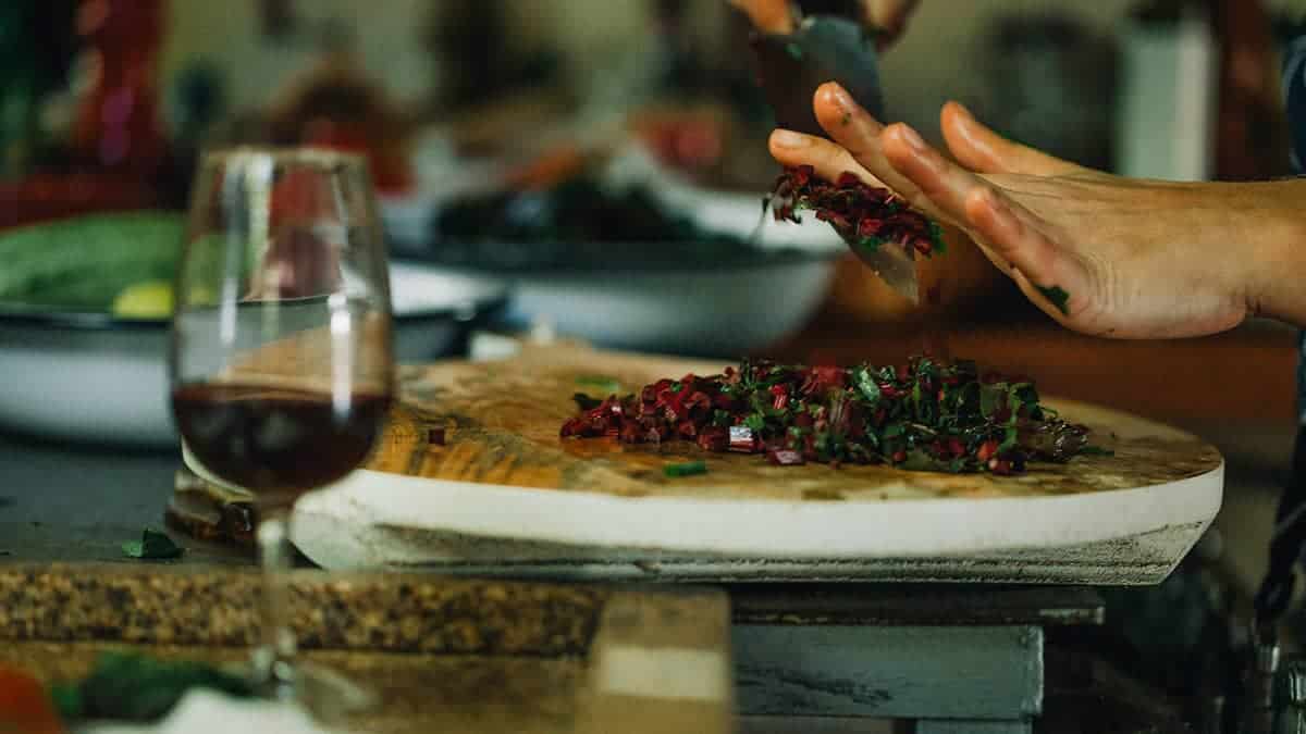 Mãos da chef de cozinha Lis Cereja cortando beterraba e ervas em bancada de cozinha
