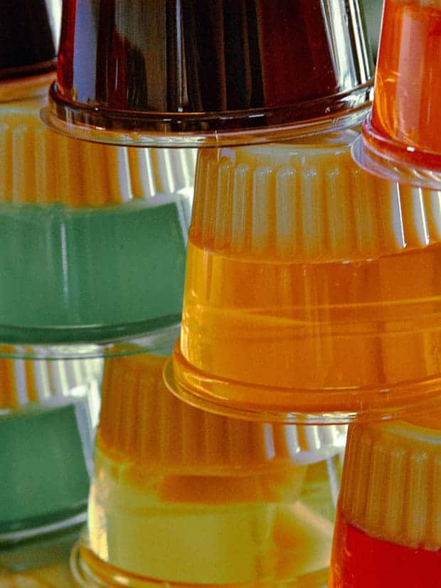 Vários potes plásticos com gelatina em cores diferentes, empilhados.