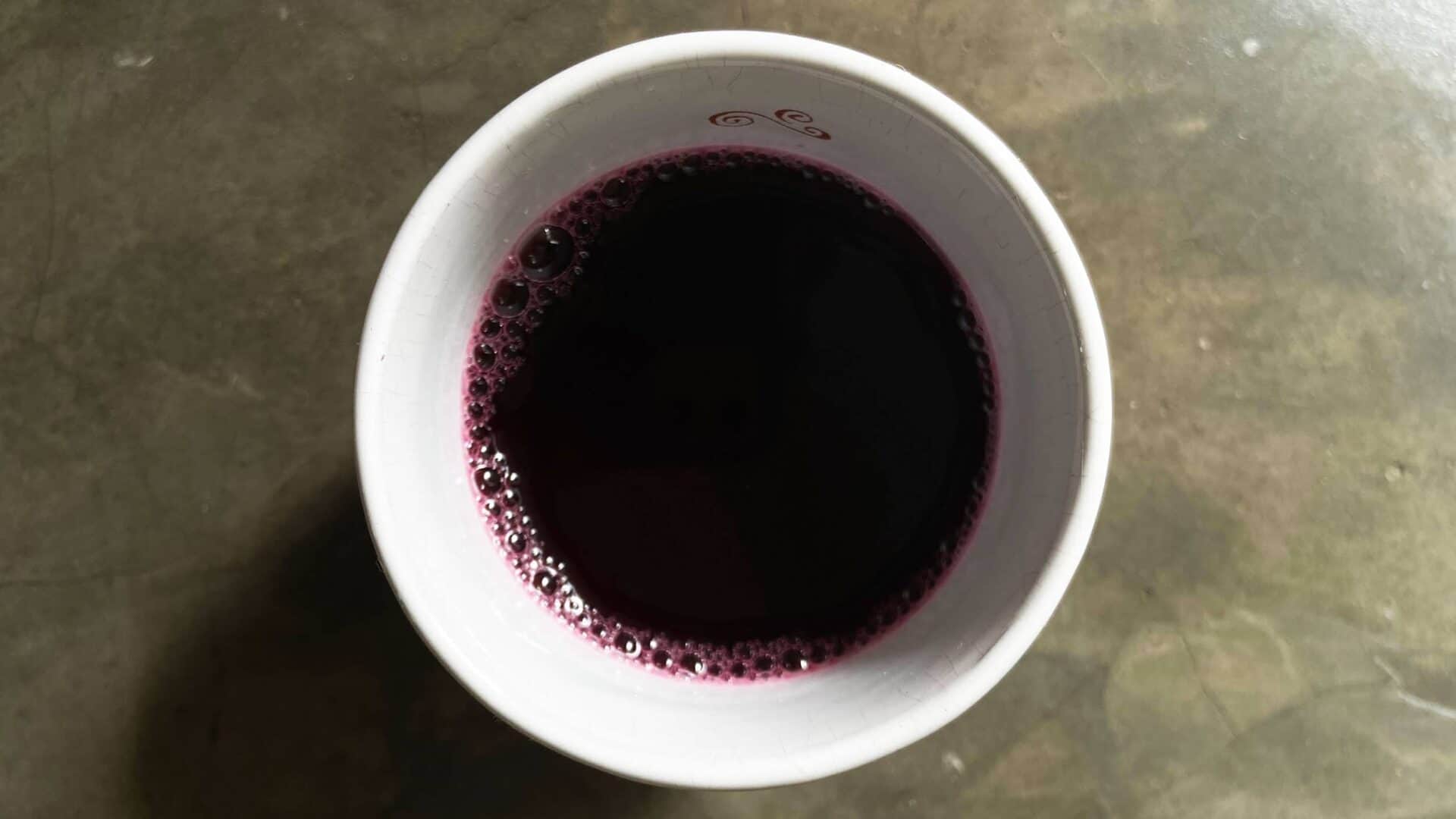 Copo com suco de uva, vista de cima, sobre superfície de concreto