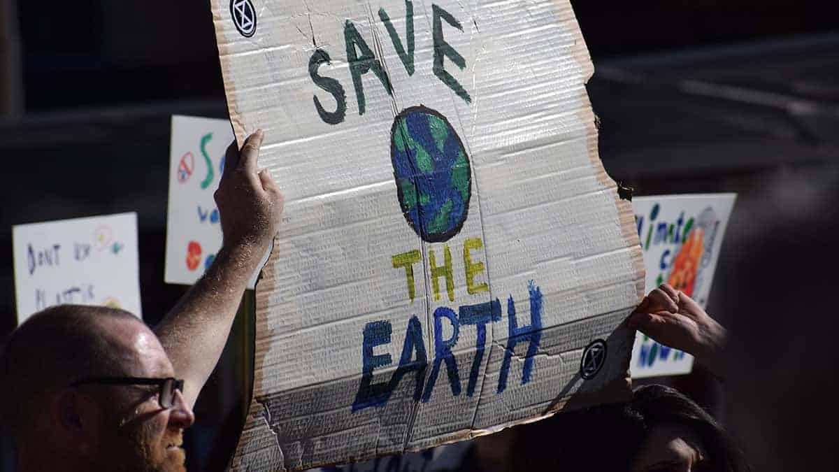 Homem segura cartaz em manifestação pelo clima, com os dizeres: "Save the Earth"