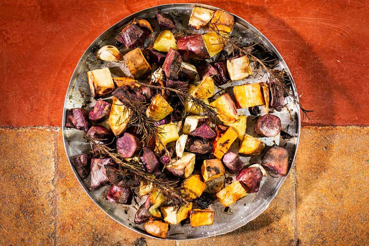 Batatas, batatas-doce roxas e laranjas assadas, com ramas de alecrim, sal e azeite