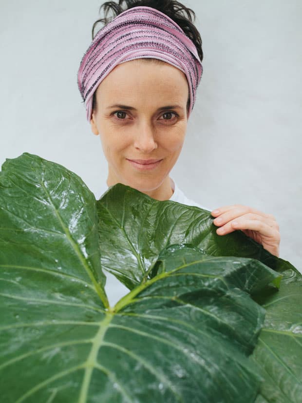 A chef Helena Rizzo posa com folhas de taioba, uma PANC (Planta Alimentícia Não Convencional)