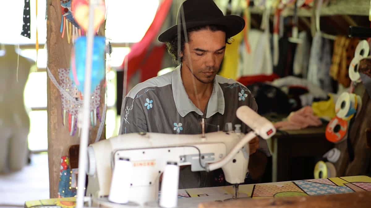 O estilista e poeta Teko Semente costurando em seu atelier