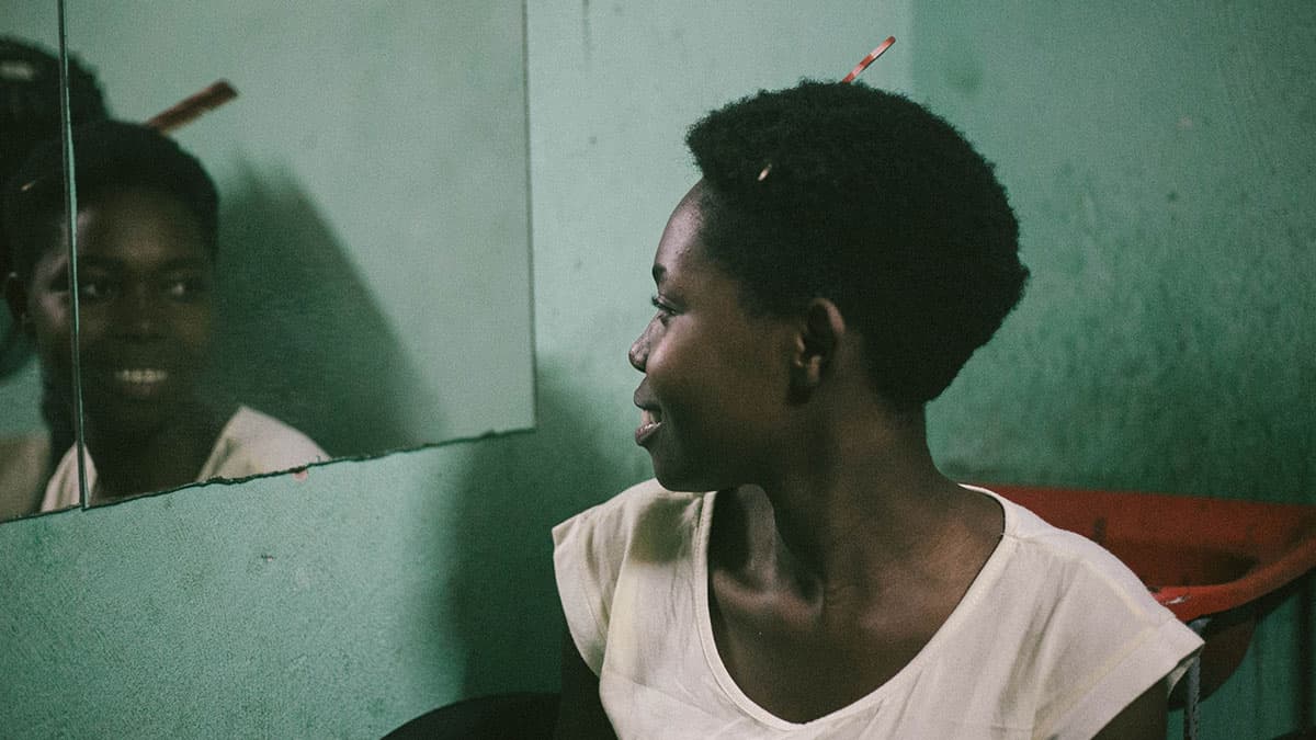Mulher negra com pente no cabelo, se olhando no espelho. Foto: Juh Almeida